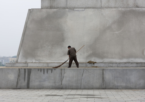 North Korean man with a broom at the bottom of the Juche tower, Pyongan Province, Pyongyang, North Korea