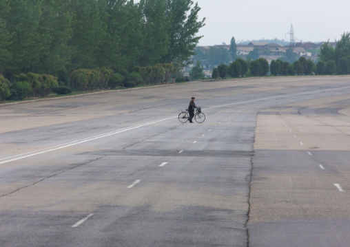 North Korean man crossing an empty highway with his bicycle, Pyongan Province, Pyongyang, North Korea