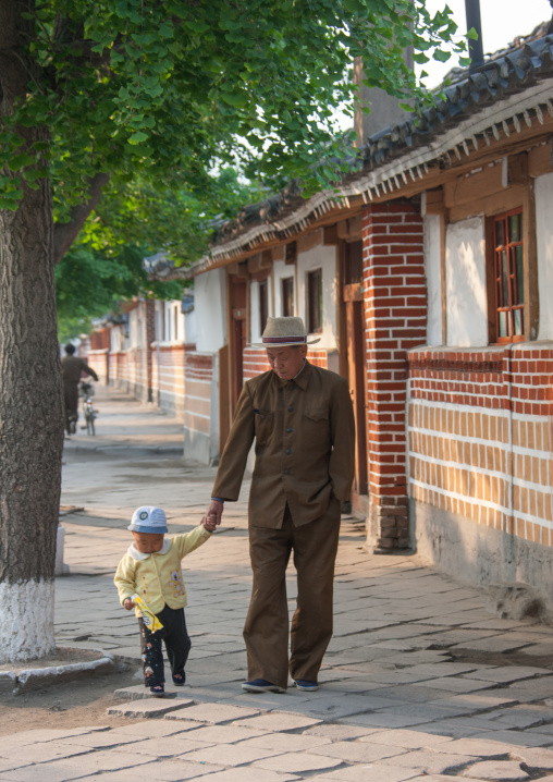 North Korean man with a child walking in the street, North Hwanghae Province, Kaesong, North Korea