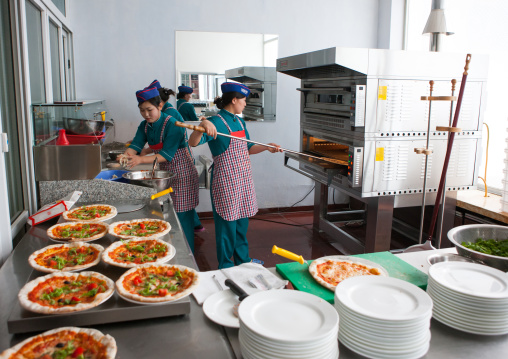 North Korean pizzeria cook putting a pizza in the oven in an italian restaurant, Pyongan Province, Pyongyang, North Korea