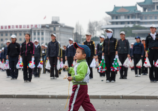 Boy passing in front of young North Korean women during a mass games rehearsal in Kim il Sung square, Pyongan Province, Pyongyang, North Korea
