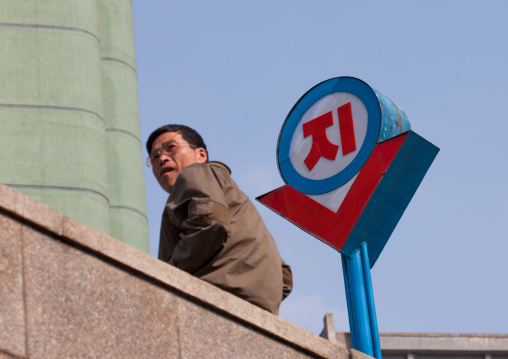 North Korean man in front of a subway sign in the street, Pyongan Province, Pyongyang, North Korea