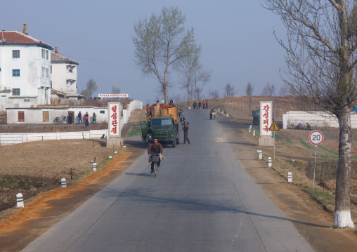 Rural road in the countryside with propaganda slogans saying union in a soul and powerful and prosperous country, South Pyongan Province, Nampo, North Korea