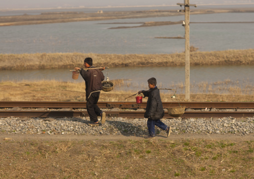 North Korean boys carrying food in baskets along a railway, Pyongan Province, Pyongyang, North Korea