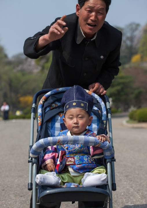 Portrait of a North Korean father with his one year old son in a baby-buggy, Pyongan Province, Pyongyang, North Korea