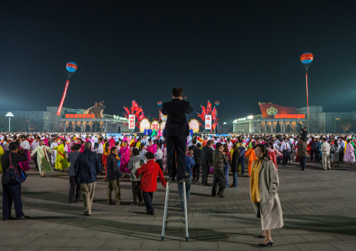 Man on a ladder taking pictures of North Korean students dancing to celebrate april 15 the birth anniversary of Kim Il-sung, Pyongan Province, Pyongyang, North Korea