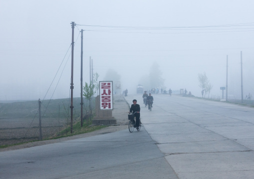 Rural road in the mist in the countryside with a slogan saying escort braving death, Kangwon Province, Chonsam Cooperative Farm, North Korea