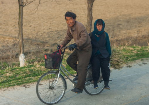 North Korean couple riding a bicycle in the countryside, Kangwon Province, Chonsam Cooperative Farm, North Korea