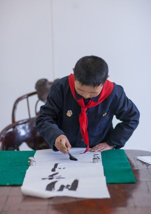 North Korean pioneer boy in a calligraphy workshop in Mangyongdae children's palace, Pyongan Province, Pyongyang, North Korea