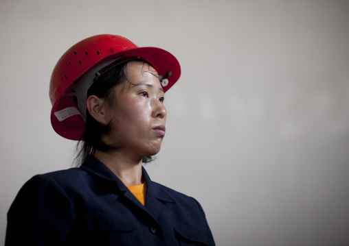 North Korean worker woman wearing a red helmet in a factory, South Pyongan Province, Nampo, North Korea