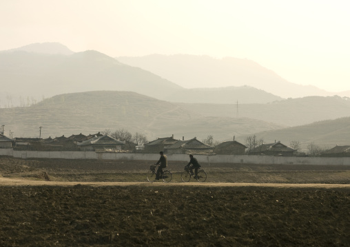 North Korean men cycling in the countryside, South Pyongan Province, Nampo, North Korea