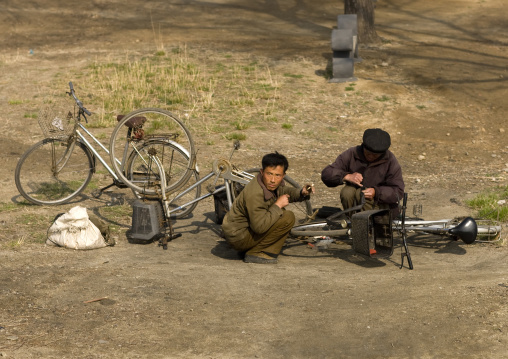North Korean men repairing bicycles along the road, South Pyongan Province, Nampo, North Korea