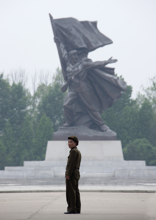 North Korean man standing in front of a sioldier statue, Pyongan Province, Pyongyang, North Korea