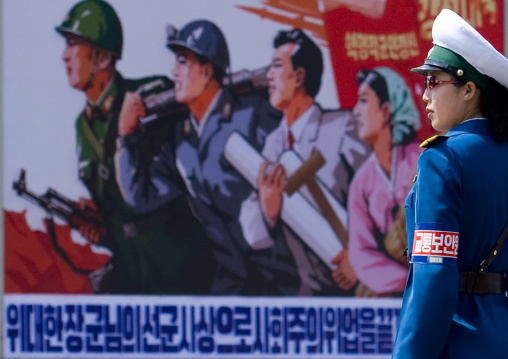 North Korean female traffic officer in front of a propaganda billboard in the street, Pyongan Province, Pyongyang, North Korea