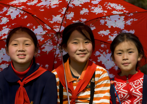 Three North Korean young pioneers under an umbrella, Pyongan Province, Pyongyang, North Korea
