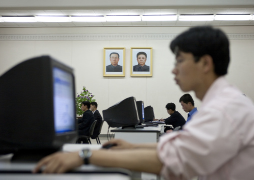 North Korean man using a computer under the Dear Leaders pictures in the Grand people's study house, Pyongan Province, Pyongyang, North Korea