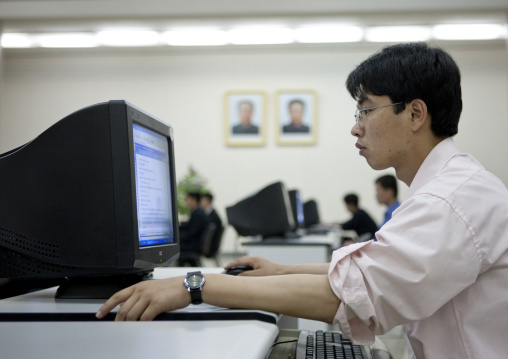 North Korean man using a computer under the Dear Leaders pictures in the Grand people's study house, Pyongan Province, Pyongyang, North Korea