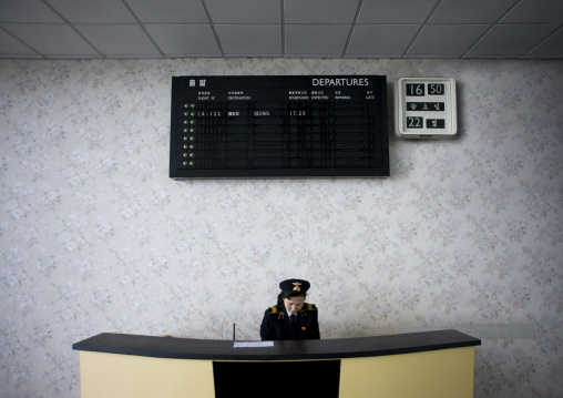 North Korea airport employee in Sunan international airport below the departures billboard, Pyongan Province, Pyongyang, North Korea