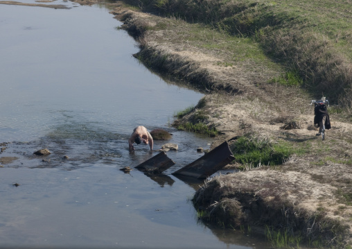 North Korean man having a bath in a cold river in the countryside, Kangwon Province, Wonsan, North Korea