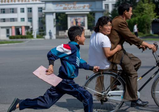North Korean boy running after a couple riding a bicycle, Pyongan Province, Pyongyang, North Korea