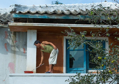 North Korean man painting his house, South Hamgyong Province, Hamhung, North Korea
