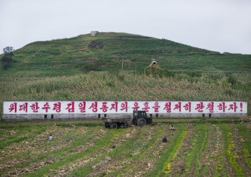 North Korean tractor in front of a propaganda billboard in a farm, South Hamgyong Province, Hamhung, North Korea