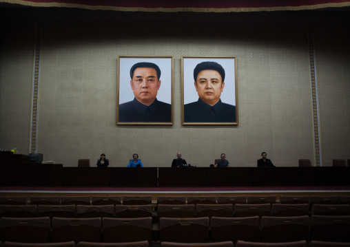 Tourists posing below the portraits of the Leaders in a conference room of the Grand people's study house, Pyongan Province, Pyongyang, North Korea