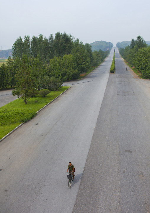 North Korean man riding a bicycle on an empty highway, North Hwanghae Province, Kaesong, North Korea