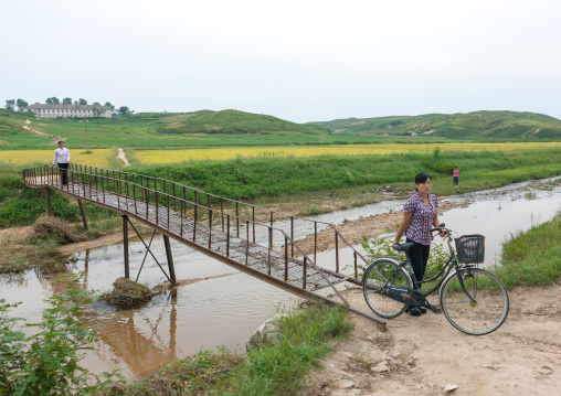 North Korean woman with a bicycle crossing a bridge, North Hwanghae Province, Kaesong, North Korea