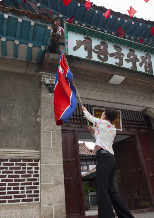 North Korean woman raising flag on a restaurant, North Hwanghae Province, Kaesong, North Korea