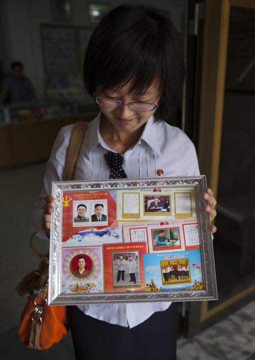North Korean woman showing Kim jong-un postage stamps, North Hwanghae Province, Kaesong, North Korea