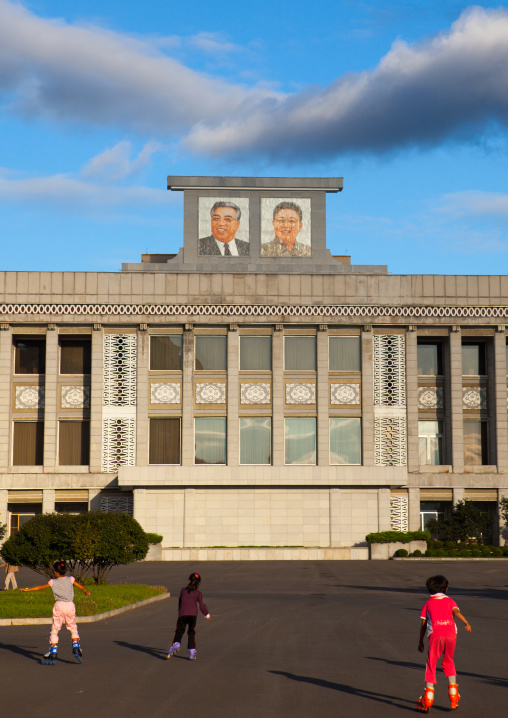 North Korean children roller skating in front of the portraits of the Dear Leaders, Pyongan Province, Pyongyang, North Korea