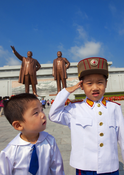 North Korean boy dressed as soldier in front of the two statues of the Dear Leaders in the Grand monument on Mansu hill, Pyongan Province, Pyongyang, North Korea