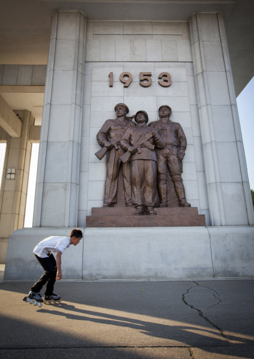 North Korean teenage boy roller skating in front of monument to the victorious fatherland liberation war museum, Pyongan Province, Pyongyang, North Korea