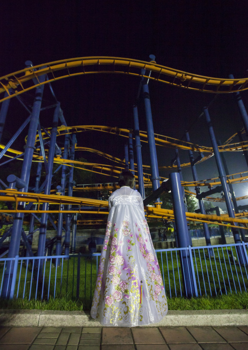 North Korean woman in choson-ot in front of a roller coaster at Kaeson youth park, Pyongan Province, Pyongyang, North Korea