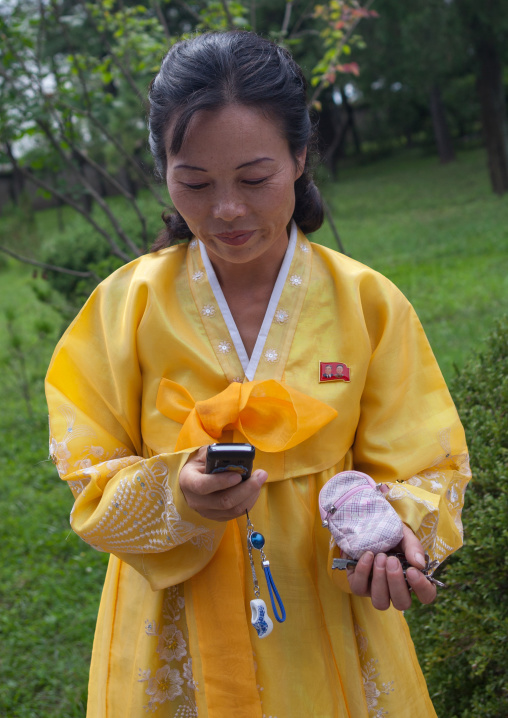 North Korean woman in yellow choson-ot using a mobile phone, South Hamgyong Province, Hamhung, North Korea
