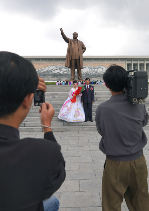 Cameraman and photogrpaher with a North Korean couple celebrating their wedding in front of Kim il Sung statue in Mansudae Grand monument, Pyongan Province, Pyongyang, North Korea