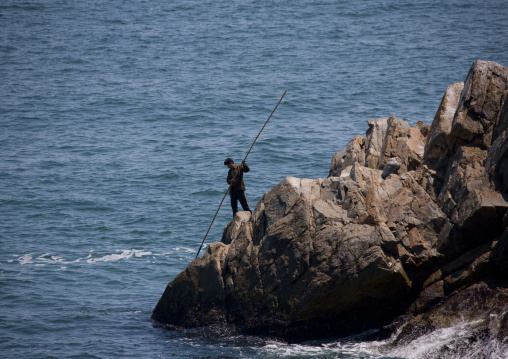 North Korean man on rocks fishing, North Hamgyong Province, Chilbo Sea, North Korea