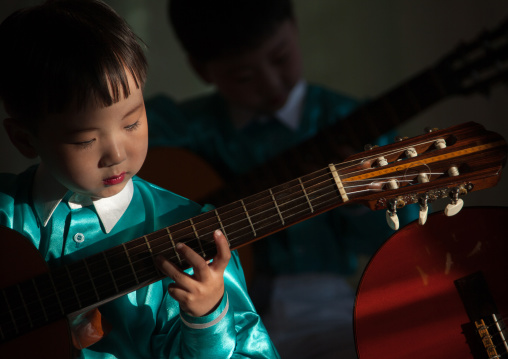 North Korean young boy playing guitar  in Tchang Gwang school, North Hamgyong Province, Chongjin, North Korea