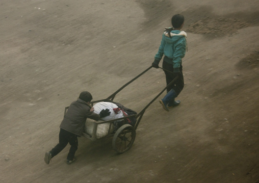North Korean children pushing a heavy cart in the street, North Hamgyong Province, Chongjin, North Korea