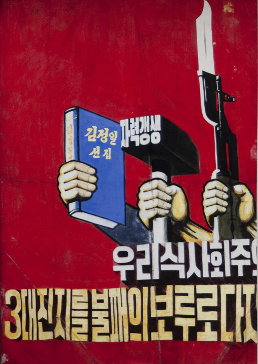North Korean propaganda billboard with a book a hammer and a gun, Pyongan Province, Pyongyang, North Korea