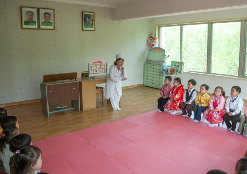North Korean teacher under the official portraits of the Dear Leaders in a classroom in Kim Jong suk school, Pyongan Province, Pyongyang, North Korea