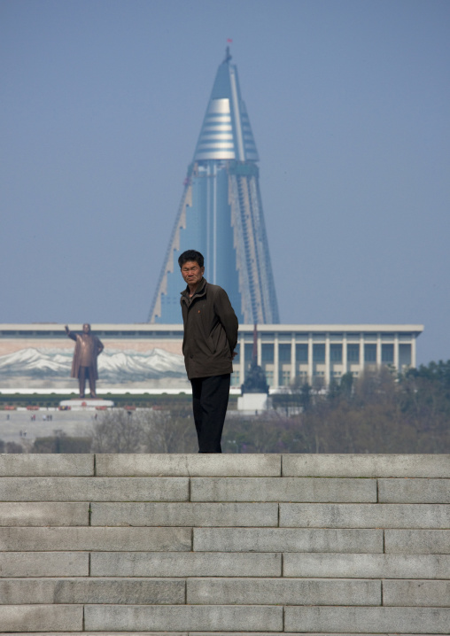 North Korean man with Ryugyong hotel and Mansudae Grand monument in the background, Pyongan Province, Pyongyang, North Korea