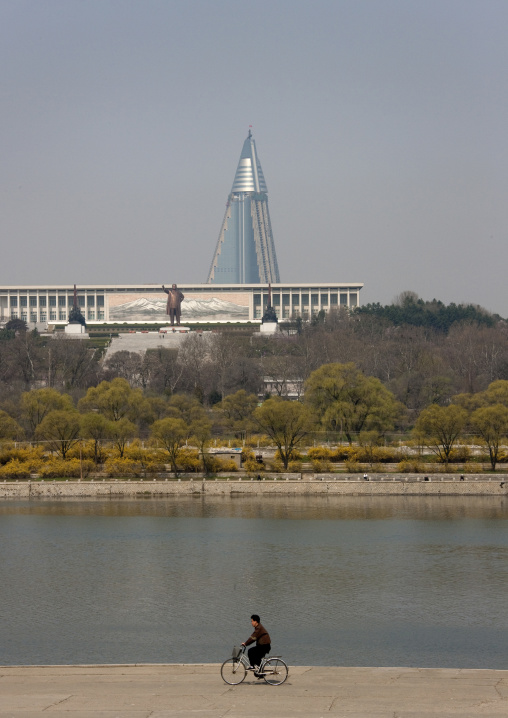 North Korean man passing along Taedong river with Ryugyong hotel in the background, Pyongan Province, Pyongyang, North Korea