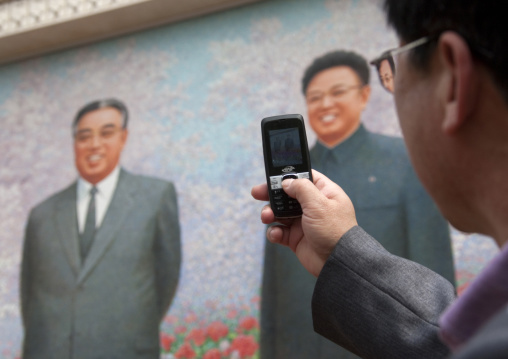 North Korean man taking a picture with his mobile phone at Kimilsungia exhibition, Pyongan Province, Pyongyang, North Korea
