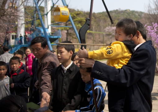 North Korean boy and father shooting with a bow in Taesongsan funfair, Pyongan Province, Pyongyang, North Korea