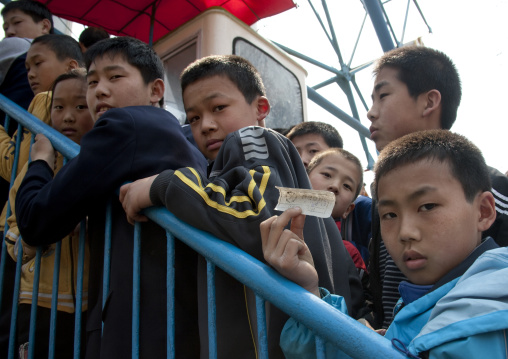 North Korean children queueing to ride the big wheel at Taesongsan funfair, Pyongan Province, Pyongyang, North Korea