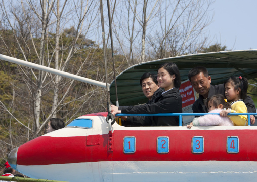 North Korean people having fun on a plane attraction in Taesongsan funfair, Pyongan Province, Pyongyang, North Korea