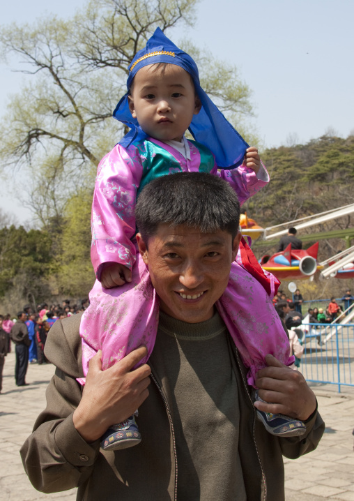 North Korean father carrying his one year old son in traditional clothing on his shoulders, Pyongan Province, Pyongyang, North Korea