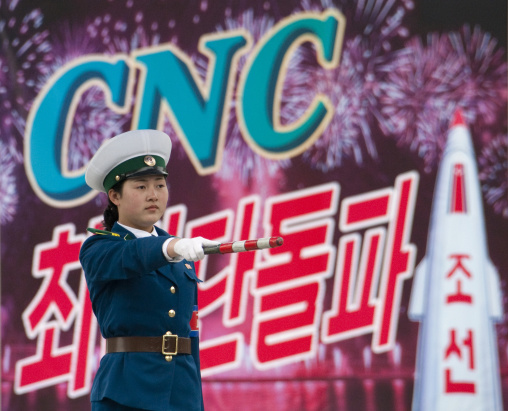 North Korean traffic security officer in blue uniform in front of a propaganda billboard, Pyongan Province, Pyongyang, North Korea